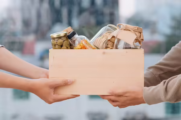 a person gives a box of food items to another person