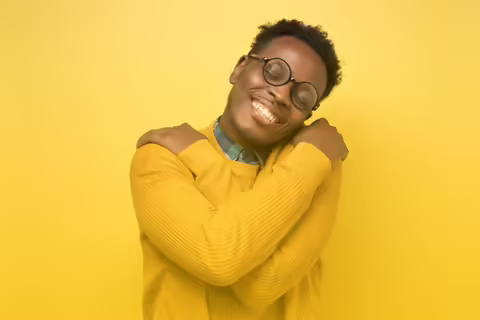 young man smiling hugging himself